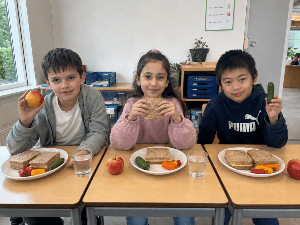 Drie kinderen met gezonde lunch op school