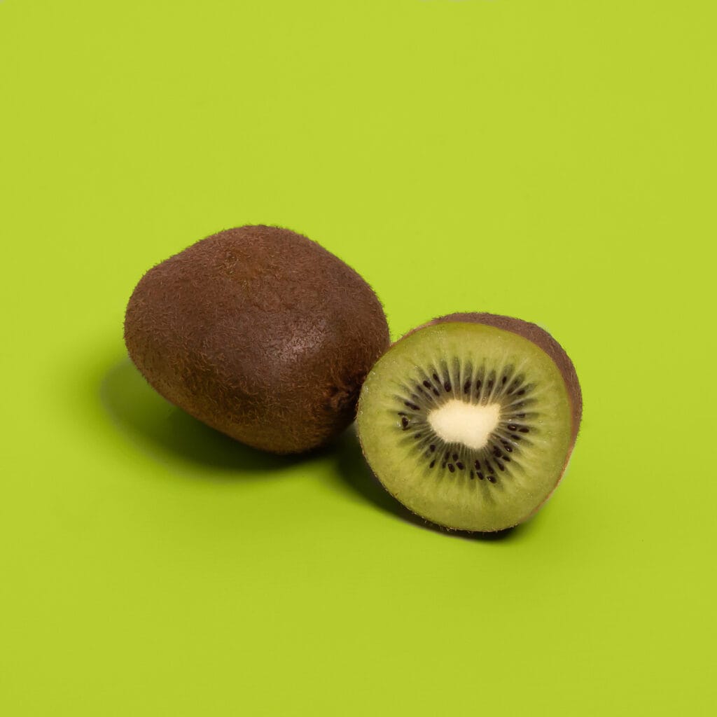 Hele en doorgesneden kiwi op groene achtergrond