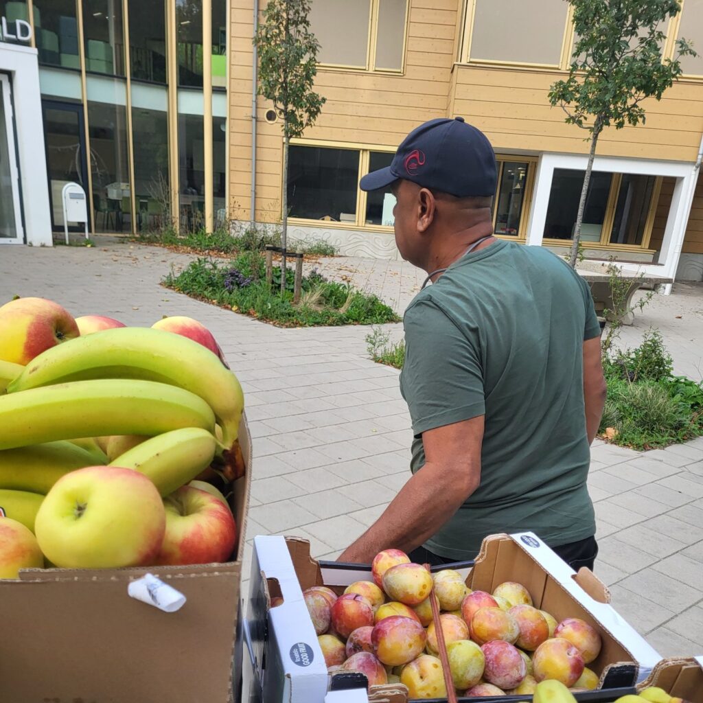 Man bij kraam met bananen, appels en pruimen