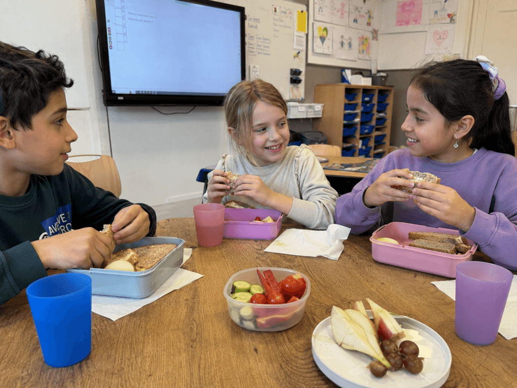 Drie kinderen eten samen lunch in klaslokaal